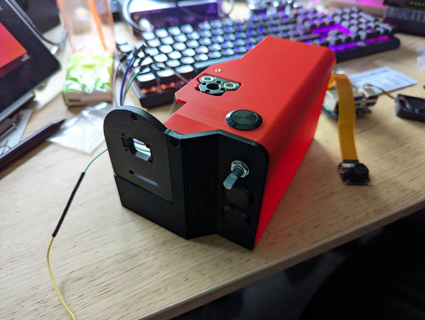 The printed red and black body part-assembled on a desk, with the buttons and encoder fitted