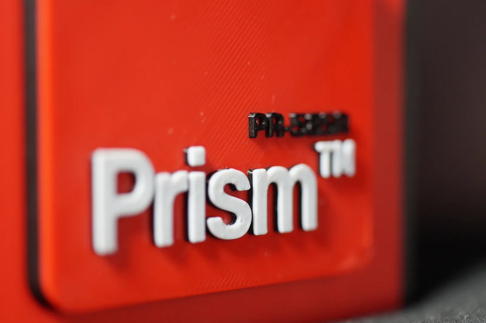 Close-up of the raised Prism badge and PR-585R model name on the red side panel